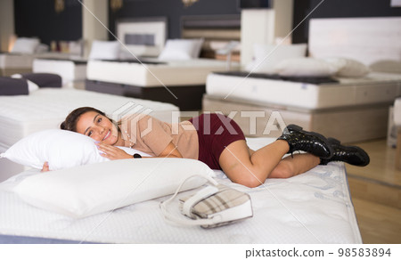 Female customer lying on mattress in store Female customer lying on mattress in store 98583894