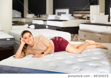 Ordinary woman testing softness of new mattress Ordinary woman testing softness of new mattress 98584078