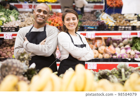 Positive latin supermarket workers with hands folded on chest in fruit section Positive latin supermarket workers with hands folded on chest in fruit section 98584079
