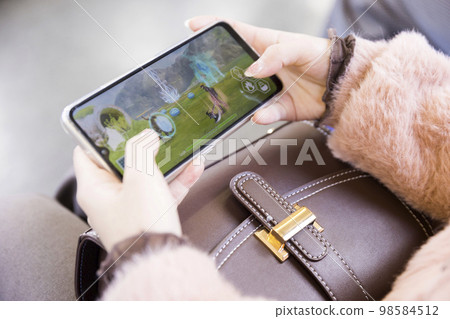 一個年輕女人的手在火車上玩智能手機遊戲 98584512