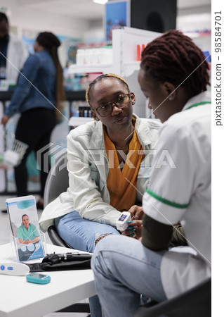 Pharmacist consultation, patient pulse oximeter measurement. Cardiac disease diagnosis, woman heartbeat examining in drugstore, pharmacy store visit, chemist and client conversation 98584701