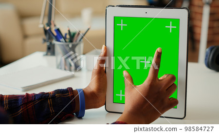 Female entrepreneur vertically holding isolated greenscreen on digital tablet, looking at blank chroma key display with mockup background. Using copy space on portable device. Close up. Female entrepreneur vertically holding isolated greenscreen on digital tablet, looking at blank chroma key display with mockup background. Using copy space on portable device. Close up. 98584727