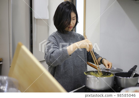 A woman boiling spaghetti 98585046
