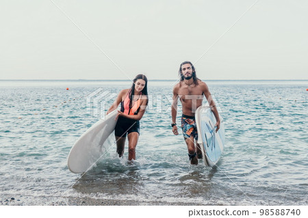 Sea woman and man on sup. Silhouette of happy young woman and man, surfing on SUP board, confident paddling through water surface. Idyllic sunset. Active lifestyle at sea or river. 98588740