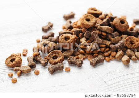 Dry food for dogs of different shapes on a white wooden background. 98588784