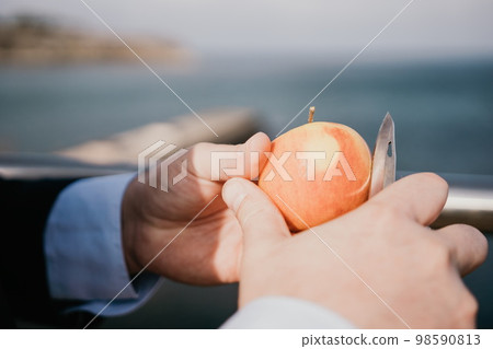 Man apple park. Hipster millennial man in a tie and jacket takes a bite out of an apple while sitting on a park bench in slow motion Young business people eating golden apples in lunch time. Man apple park. Hipster millennial man in a tie and jacket takes a bite out of an apple while sitting on a park bench in slow motion Young business people eating golden apples in lunch time. 98590813