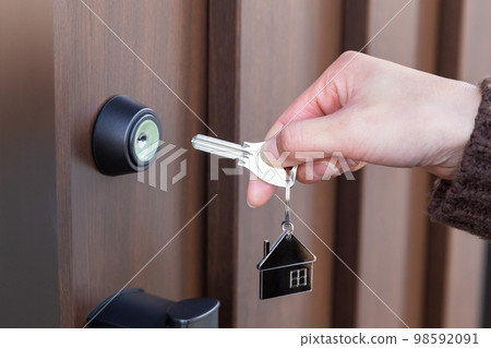 Hand of a woman who locks the front door 98592091