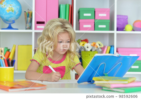 little girl studying at home at the table little girl studying at home at the table 98592606