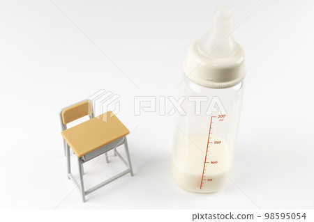 配有嬰兒奶瓶和玩具的學習桌。育兒研究圖像 98595054
