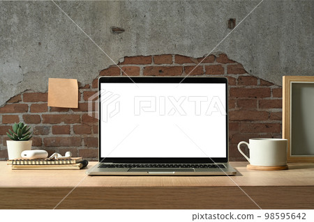 Modern industrial creative workspace with laptop computer, coffee cup, stationery and picture frame on wooden table Modern industrial creative workspace with laptop computer, coffee cup, stationery and picture frame on wooden table 98595642