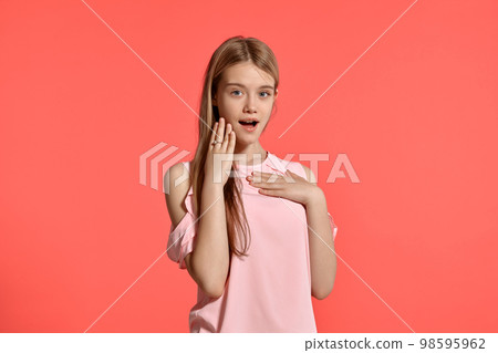 Studio portrait of a beautiful girl blonde teenager in a rosy t-shirt posing on pink background. 98595962