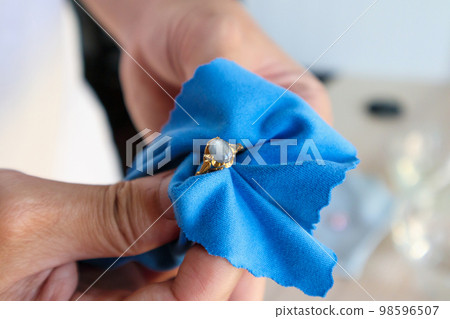 Jeweller hand polishing and cleaning gold jewelry ring with micro fiber fabric Jeweller hand polishing and cleaning gold jewelry ring with micro fiber fabric 98596507