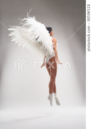 Graceful woman in underwear with feather wings levitating in air Graceful woman in underwear with feather wings levitating in air 98596528