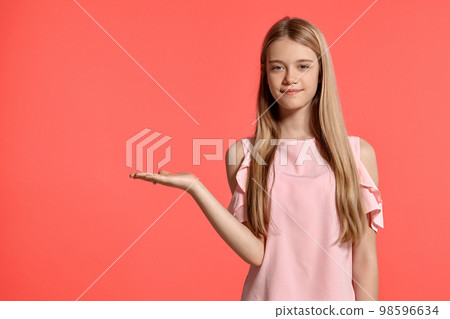 Studio portrait of a beautiful girl blonde teenager in a rosy t-shirt posing on pink background. 98596634