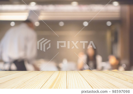 Empty wood table top with Chef cooking in restaurant kitchen abstract blurred defocused background 98597098
