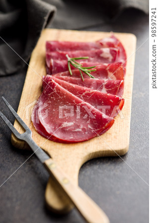 Smoked bresaola. Italian appetizer. Dried beef meat on cutting board. Smoked bresaola. Italian appetizer. Dried beef meat on cutting board. 98597241