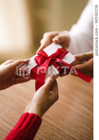 Man gives to his woman a gift box with red ribbon. Hands of man gives surprise gift box for girl. Man gives to his woman a gift box with red ribbon. Hands of man gives surprise gift box for girl. 98598336