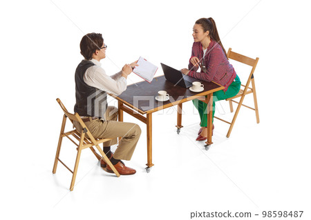 Two young people, co-workers, office workers in business style clothes isolated over white background. Teamwork, business process, support, new project concept Two young people, co-workers, office workers in business style clothes isolated over white background. Teamwork, business process, support, new project concept 98598487