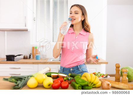 Young attractive woman drinking water at home Young attractive woman drinking water at home 98600068