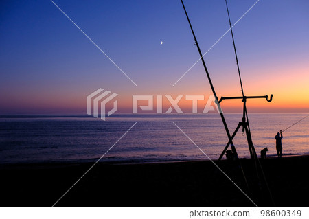 Fisherman and fishing rods by the sea at sunset, Castiglione della Pescaia, Tuscany, Maremma, Italy 98600349
