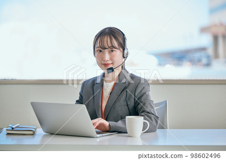 看著相機在辦公室接電話的年輕女性 98602496