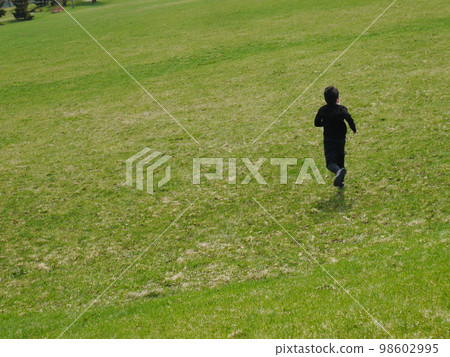 一個男孩在草坪上奔跑（後視圖） 98602995