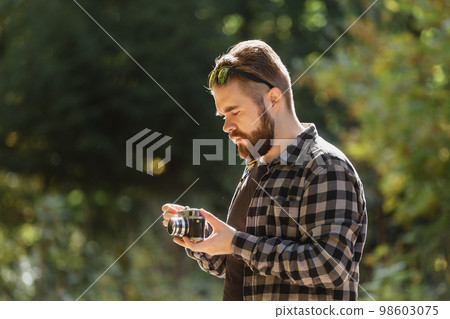 Portrait man photographer taking picture with vintage camera on city green park copy space and place for text - leisure activity and hobby concept Portrait man photographer taking picture with vintage camera on city green park copy space and place for text - leisure activity and hobby concept 98603075
