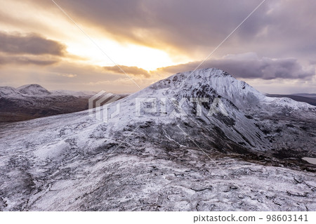 Aerial view of the snow covered Mount Errigal, the highest mountain in Donegal - Ireland. Aerial view of the snow covered Mount Errigal, the highest mountain in Donegal - Ireland. 98603141