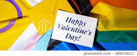 HAPPY VALENTINES DAY text Greeting card on Rainbow LGBTQIA flag made from silk material. Symbol of LGBTQ pride month. Equal rights. Peace and freedom. Support LGBTQIA community HAPPY VALENTINES DAY text Greeting card on Rainbow LGBTQIA flag made from silk material. Symbol of LGBTQ pride month. Equal rights. Peace and freedom. Support LGBTQIA community 98603652