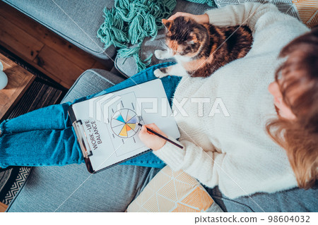 Top view relaxed young woman drawing work-life balance wheel sitting on the sofa with cat pet at home. Self-reflection and life planning. Coaching tools. Finding Balance in Your Life. Selective focus. Top view relaxed young woman drawing work-life balance wheel sitting on the sofa with cat pet at home. Self-reflection and life planning. Coaching tools. Finding Balance in Your Life. Selective focus. 98604032