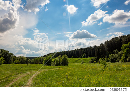 Beautiful blue sky with passing clouds over a bright green landscape Beautiful blue sky with passing clouds over a bright green landscape 98604275