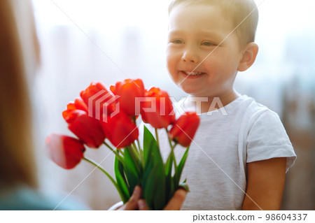 Little son congratulates mother, gives bouquet of flowers tulips. Happy mother's day. Family holiday Little son congratulates mother, gives bouquet of flowers tulips. Happy mother's day. Family holiday 98604337