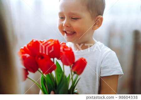 Little son congratulates mother, gives bouquet of flowers tulips. Happy mother's day. Family holiday 98604338