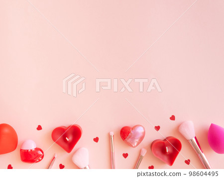Pink valentines day background with different hearts, cosmetics brushes, lipsticks, sponges on pink background. Pink valentines day background with different hearts, cosmetics brushes, lipsticks, sponges on pink background. 98604495