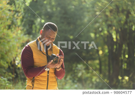 Close-up african american guy photographer taking picture with photo camera on city green park copy space and place for text - leisure activity, diversity and hobby concept Close-up african american guy photographer taking picture with photo camera on city green park copy space and place for text - leisure activity, diversity and hobby concept 98604577