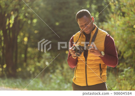 African american guy photographer taking picture with photo camera on city green park copy space - leisure activity, diversity and hobby concept 98604584