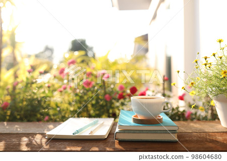 Coffee cup and pot and daisy flower on wooden table outdoor 98604680