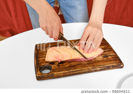 Man cuts the skin on a duck breast Man cuts the skin on a duck breast 98604831
