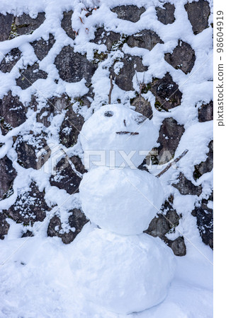 A snowman made in front of a stone wall A snowman made in front of a stone wall 98604919