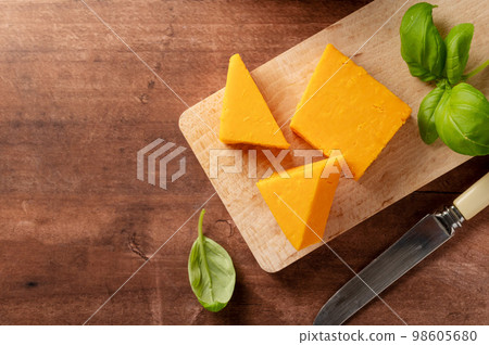 Cheddar orange cheese slices, wooden background, copy space. 98605680