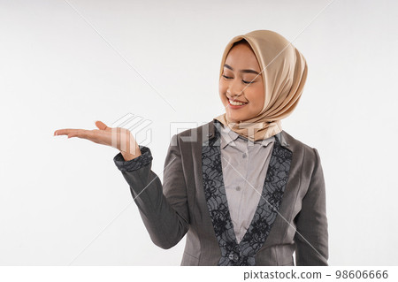 a beautiful woman with hijab raising her opened hand on her side 98606666