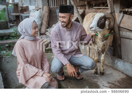 a moslem man squatting and holding the goat a moslem man squatting and holding the goat 98606690