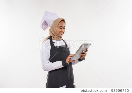 a beautiful cook with hijab looking at the tablet 98606750
