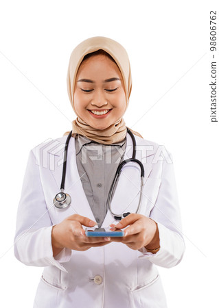 a beautiful doctor standing with cheerful face while looking at the phone a beautiful doctor standing with cheerful face while looking at the phone 98606762
