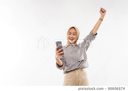 a woman with hijab smiling while standing with raised and clenched arm a woman with hijab smiling while standing with raised and clenched arm 98606874