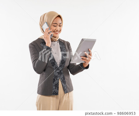 a beautiful woman with hijab standing and calling someone on phone 98606953