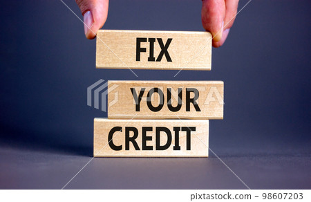 Fix your credit symbol. Concept words Fix your credit on wooden blocks on a beautiful grey table grey background. Businessman hand. Business, finacial and fix your credit concept. Copy space. Fix your credit symbol. Concept words Fix your credit on wooden blocks on a beautiful grey table grey background. Businessman hand. Business, finacial and fix your credit concept. Copy space. 98607203