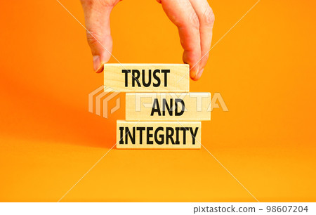 Trust and integrity symbol. Concept words Trust and integrity on wooden blocks. Businessman hand. Beautiful orange background. Business, psychological and trust and integrity concept. Copy space. Trust and integrity symbol. Concept words Trust and integrity on wooden blocks. Businessman hand. Beautiful orange background. Business, psychological and trust and integrity concept. Copy space. 98607204