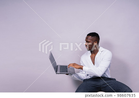 Optimistic african-american male student in casual shirt using laptop pc isolated Optimistic african-american male student in casual shirt using laptop pc isolated 98607635