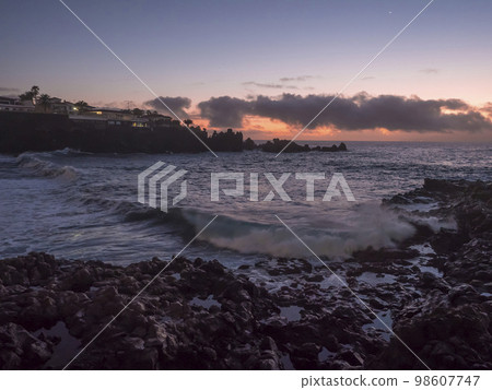 Sunset view of black sand beach Playa de la Arena with dramat orange clouds and sharp lava rock. Santiago del Teide, Tenerife, Canary Islands, Spain. 98607747